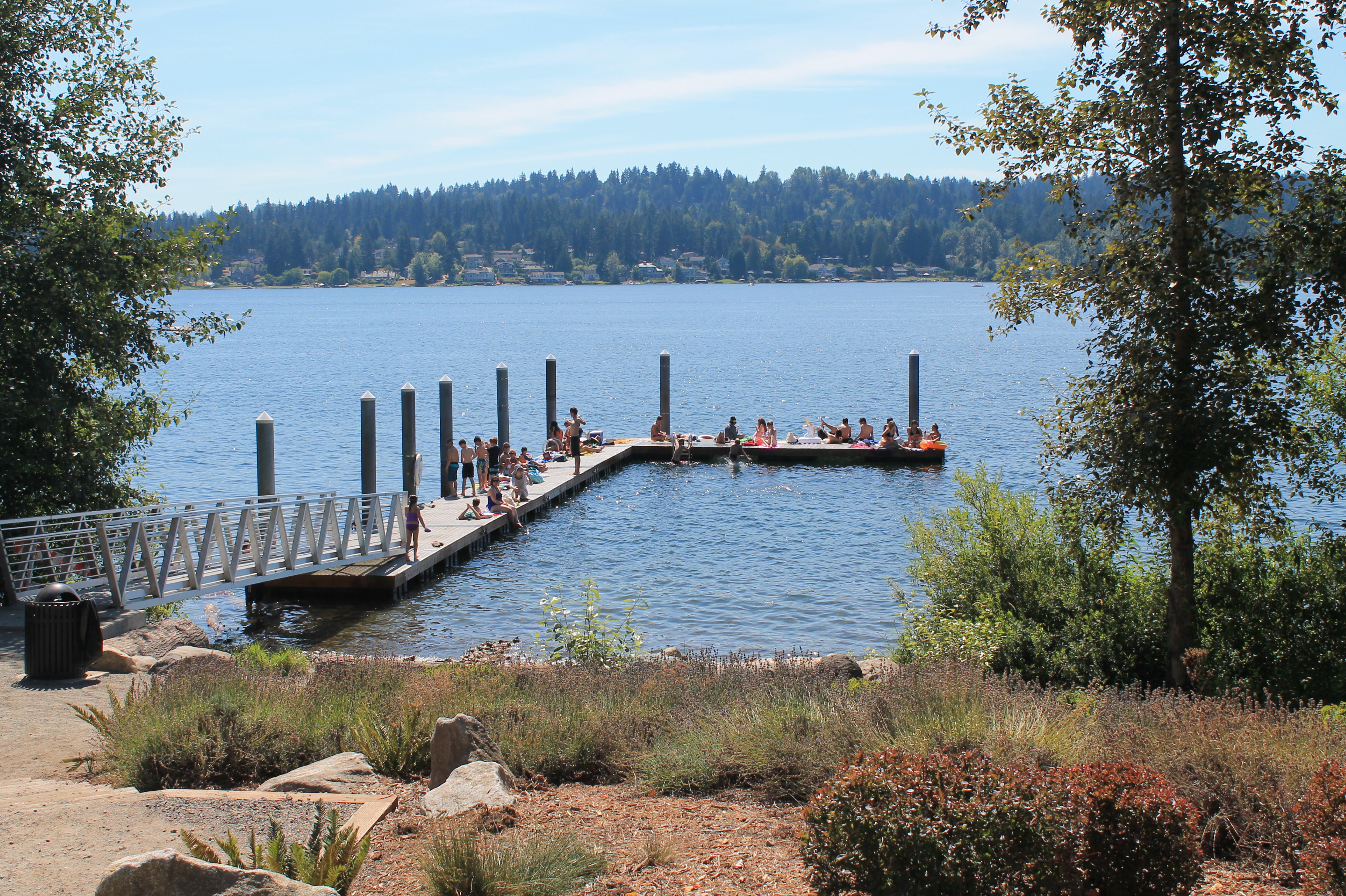 People on the dock and the beach at Sammamish Landing Park on Lake Sammamish.
