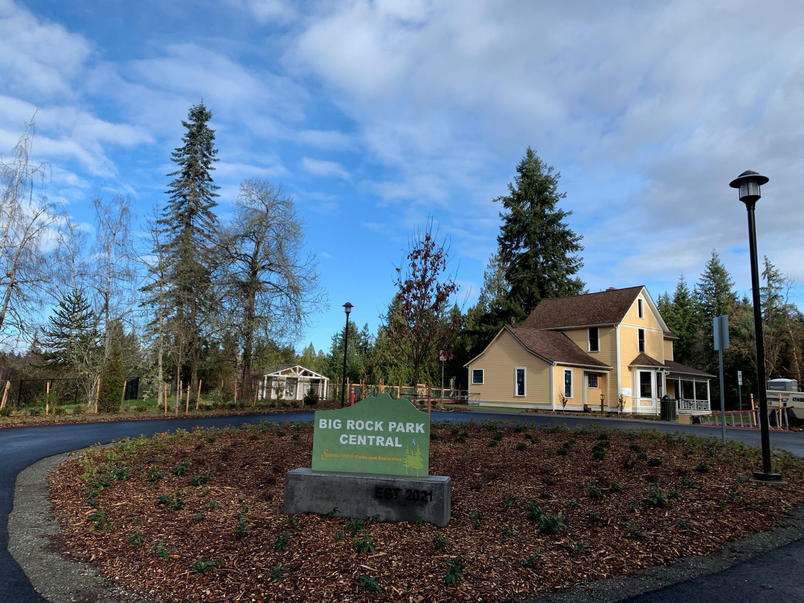 Entrance sign to Big Rock Park Central in parking circle with historic Reard Freed House visible behind