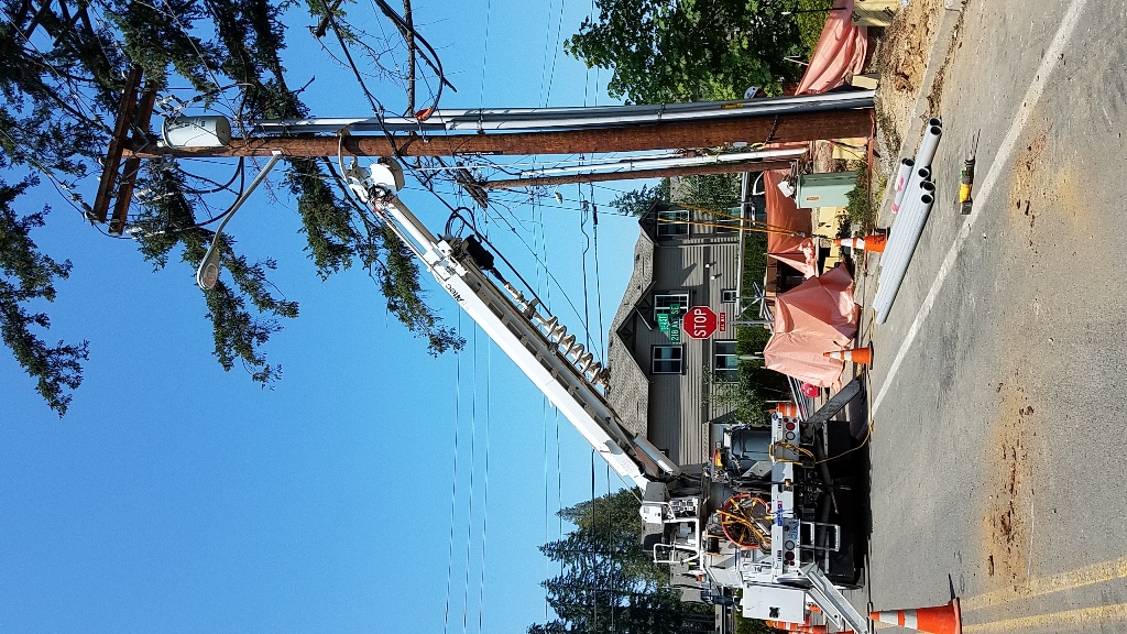 PSE truck with arm holding power pole during construction
