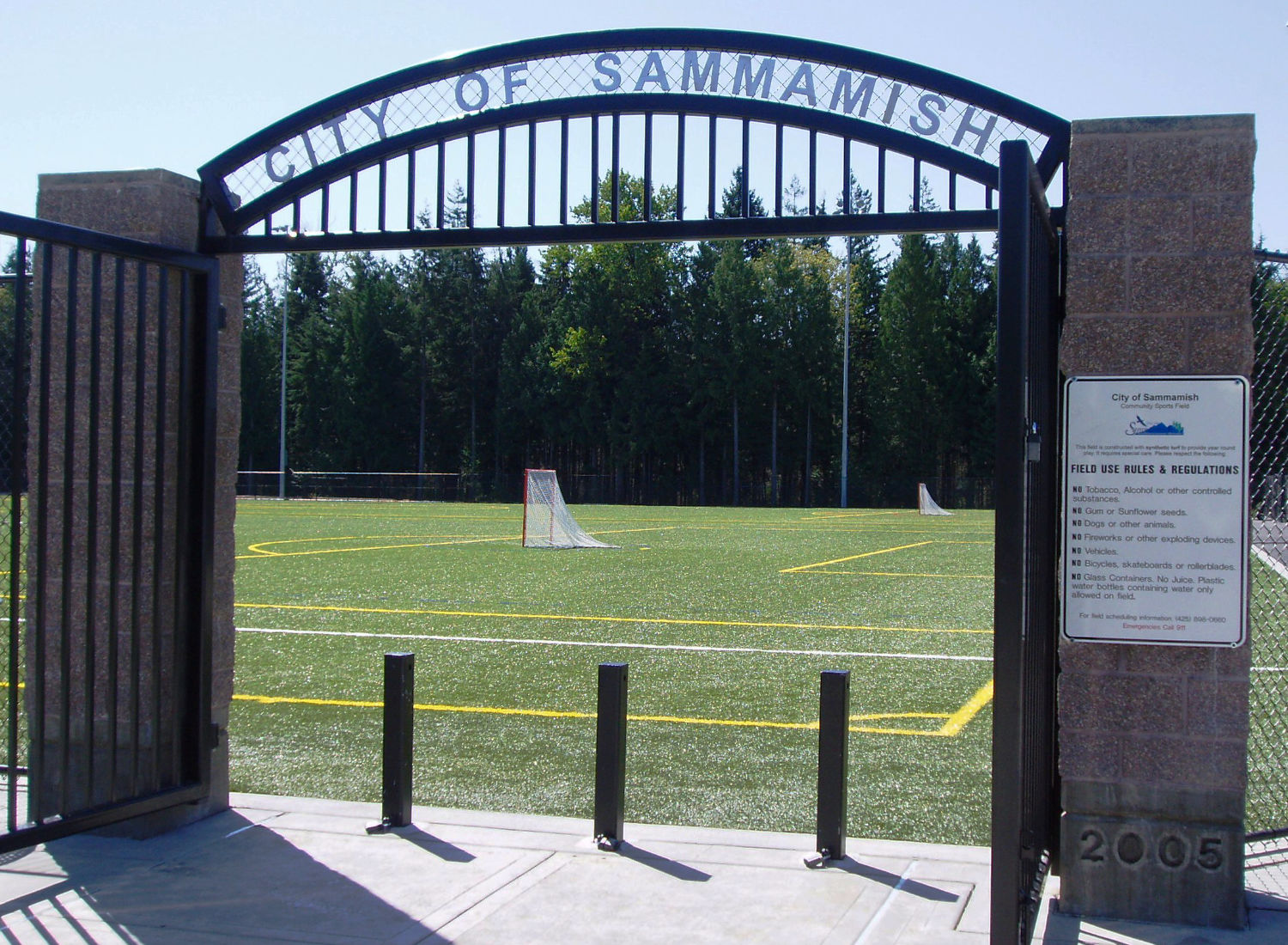 Black iron gate with masonry posts at Eastlake Community Fields opens up to a soccer field