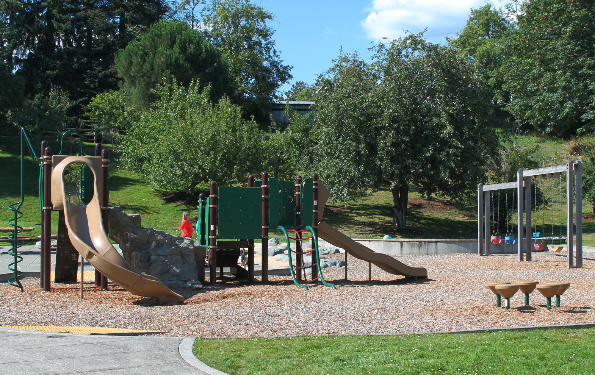Sammamish Commons playground structure containing slides and climbing bars. A swing set is close by.