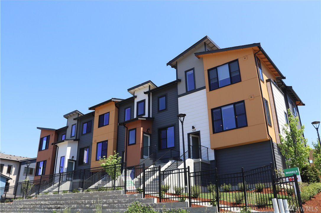 multi-colored townhome frontages with varied roofline behind metal fence