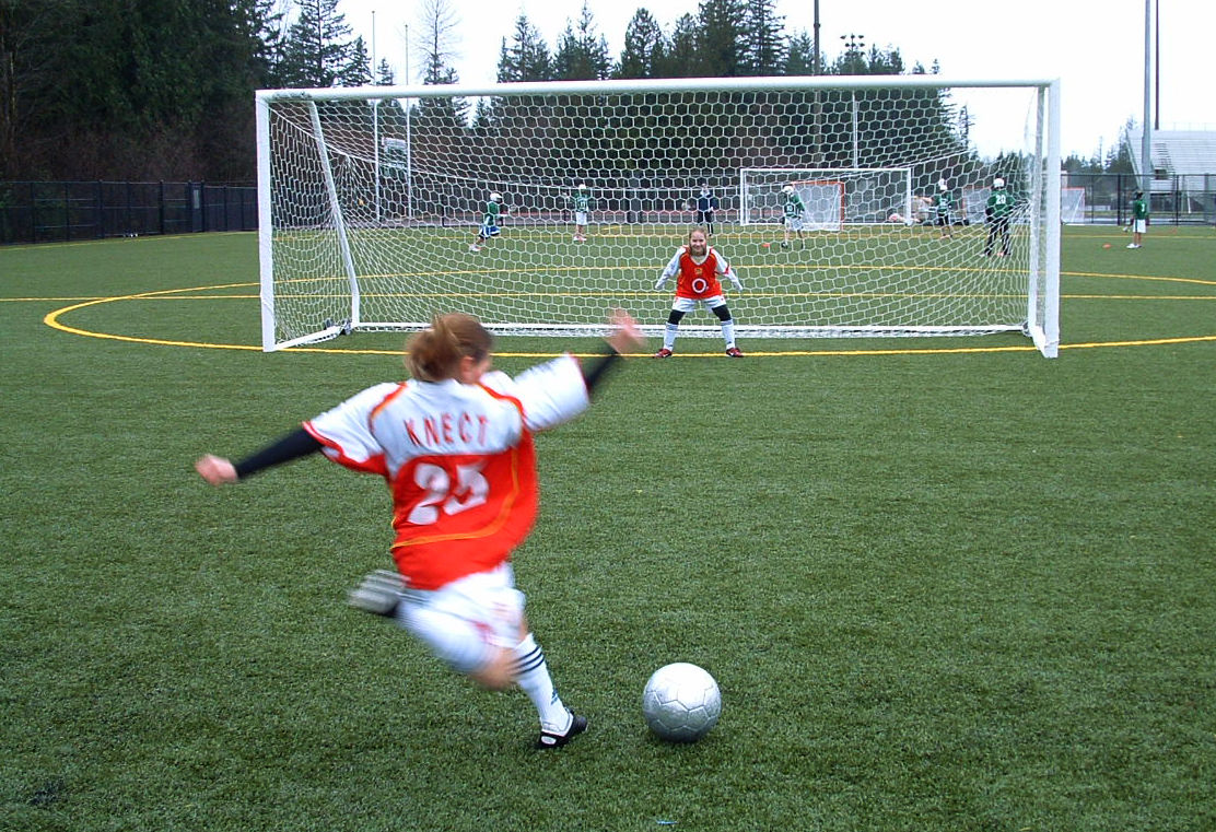 Girl in red and white uniform gets ready to attempt kicking ball into goal during a soccer game at Eastlake Community Fields