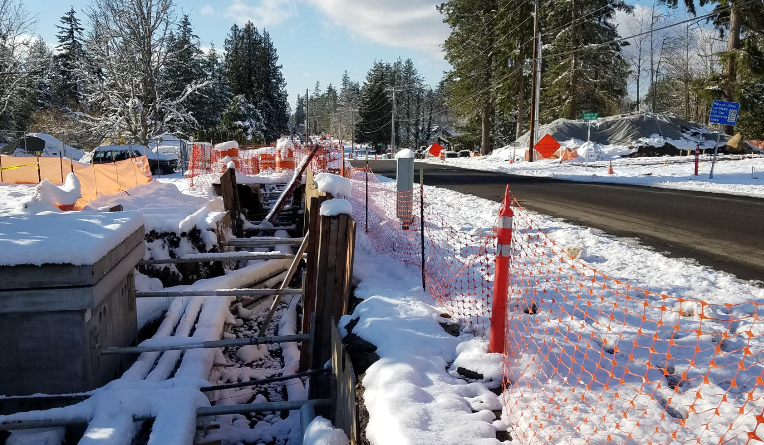 snow day at the construction site, showing a couple inches of melting snow in the trench beside a clear road