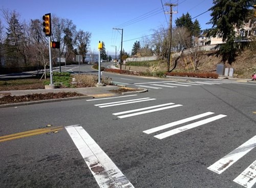 worn white thermoplastic markings for a stop line and crosswalk striping at an intersection
