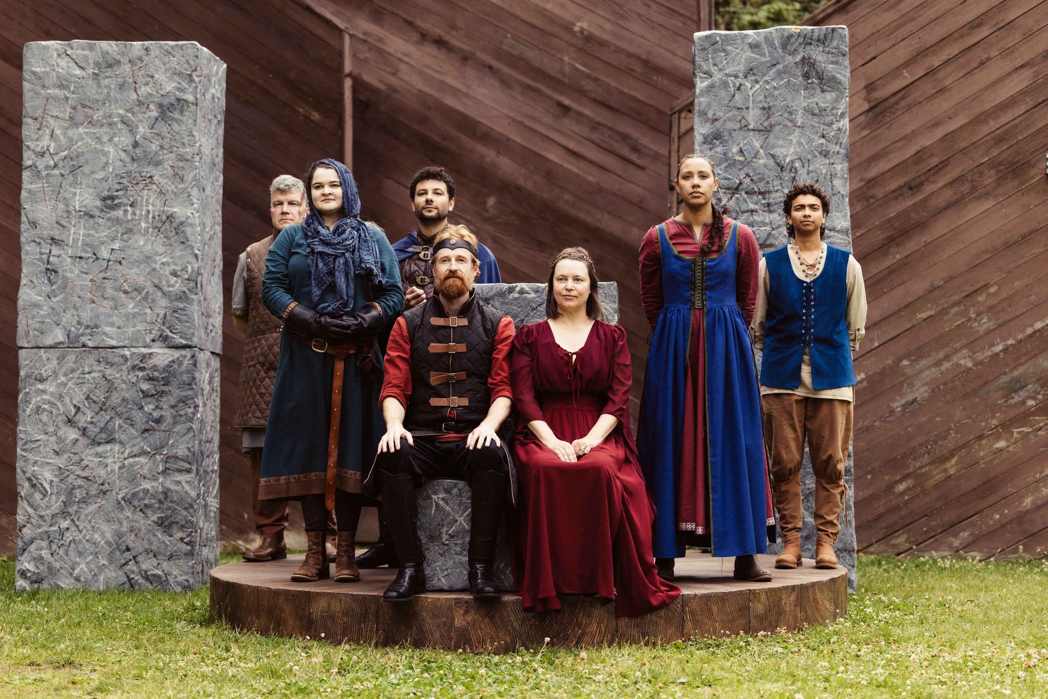 Shakespeare in the Park Macbeth actors pose, in era-specific costume, around seated King Macbeth and Queen.