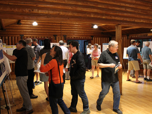 Roomful of people walking around and looking at various informational poster boards on tripods at public workshop inside Beaver Lake Lodge.