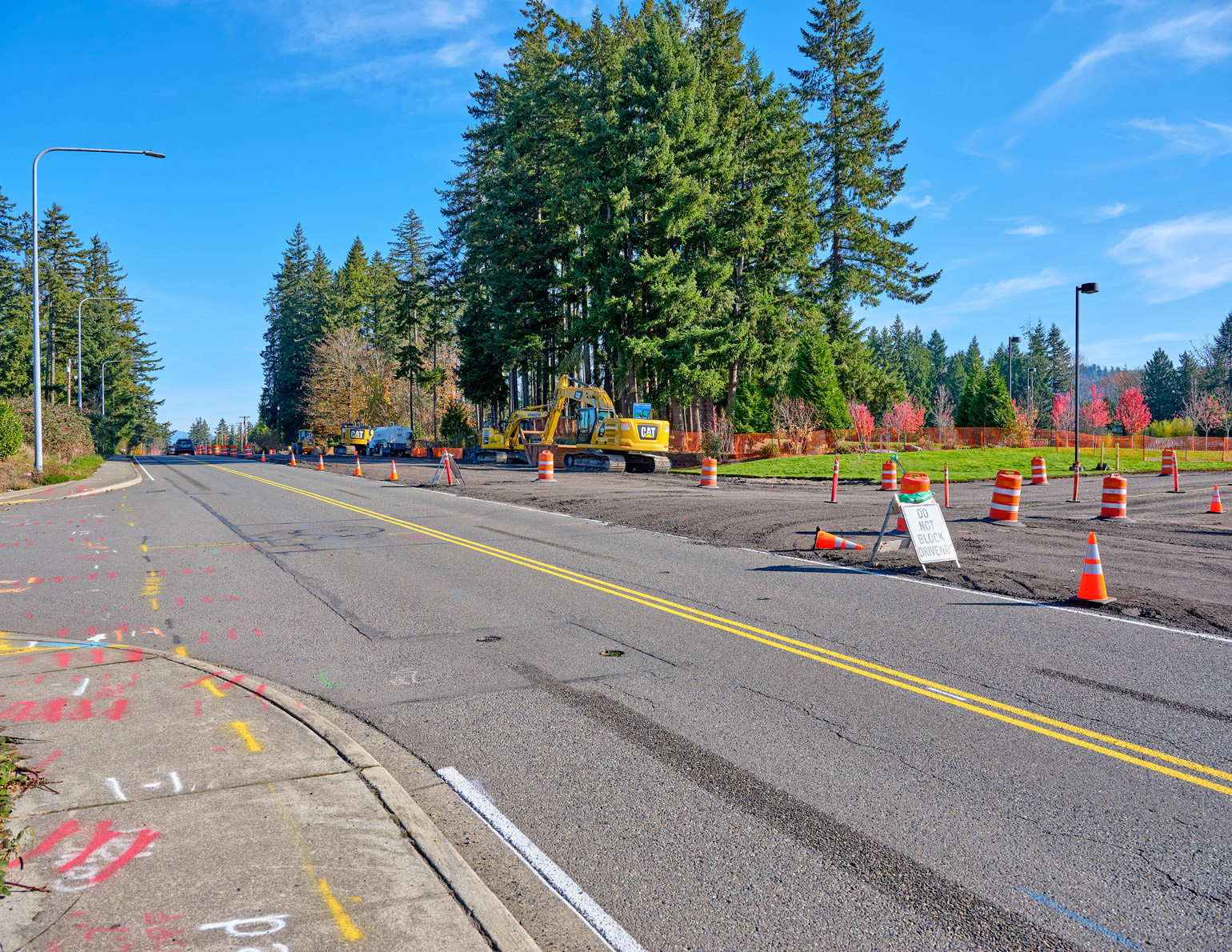 construction on Issaquah Fall City Road, with space cleared for additional work adjacent to an existing paved lane, traffic barriers lining the edge