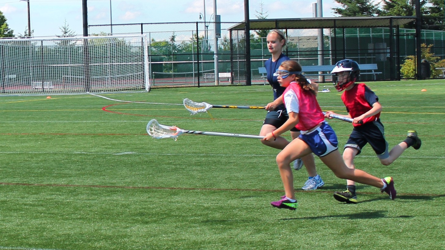 Youth on Skyline and Sammamish lacrosse team run while holding their lacrosse sticks during play