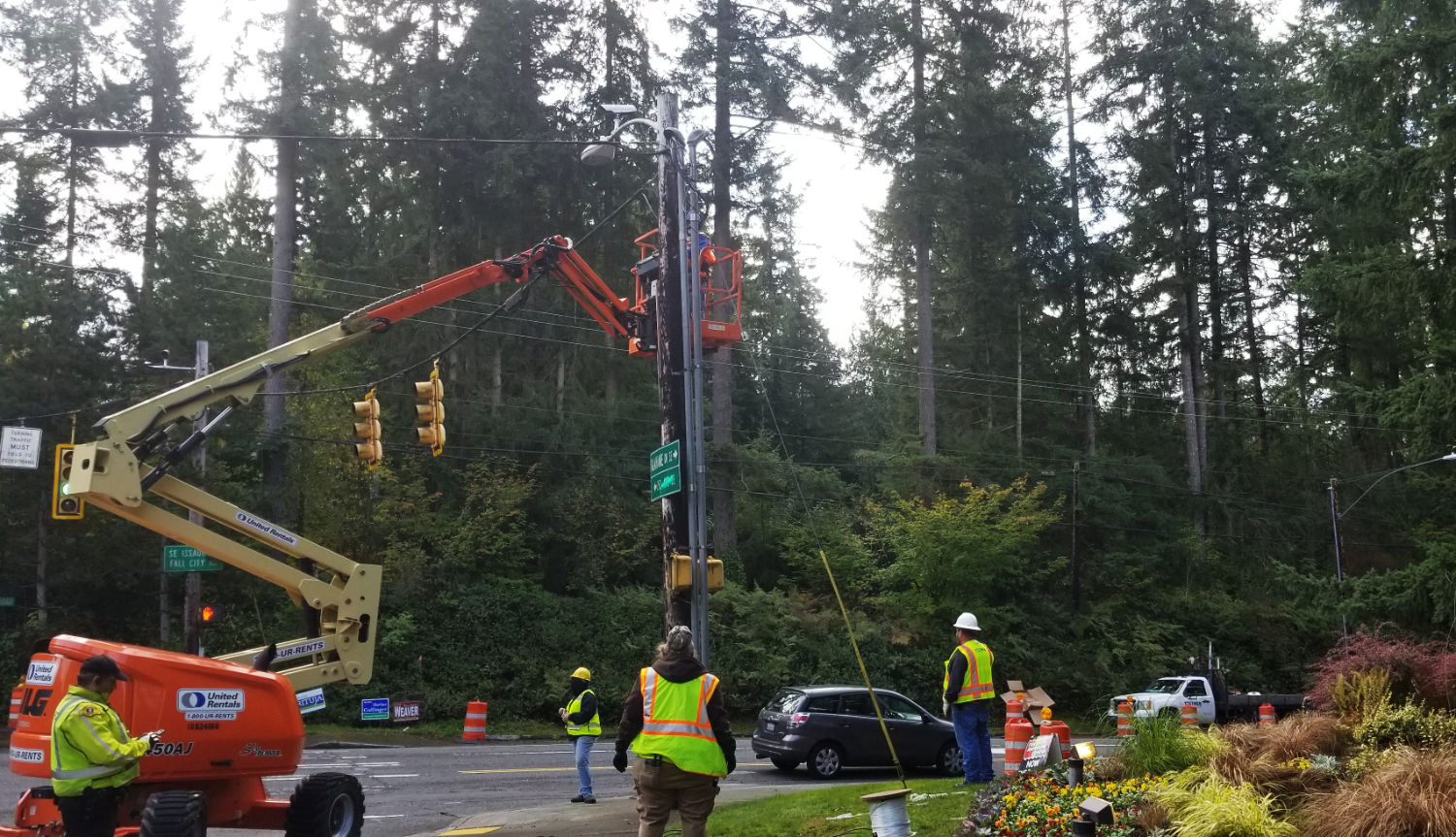workers watching elevated work occur  at an existing stoplight on Issaquah Fall City Road
