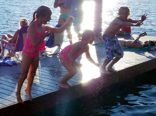 excited kids jump off a dock into the lake at Sammamish Landing