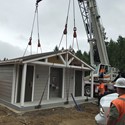 A crane being used on a building at Big Rock Park Central while construction workers watch in the foreground