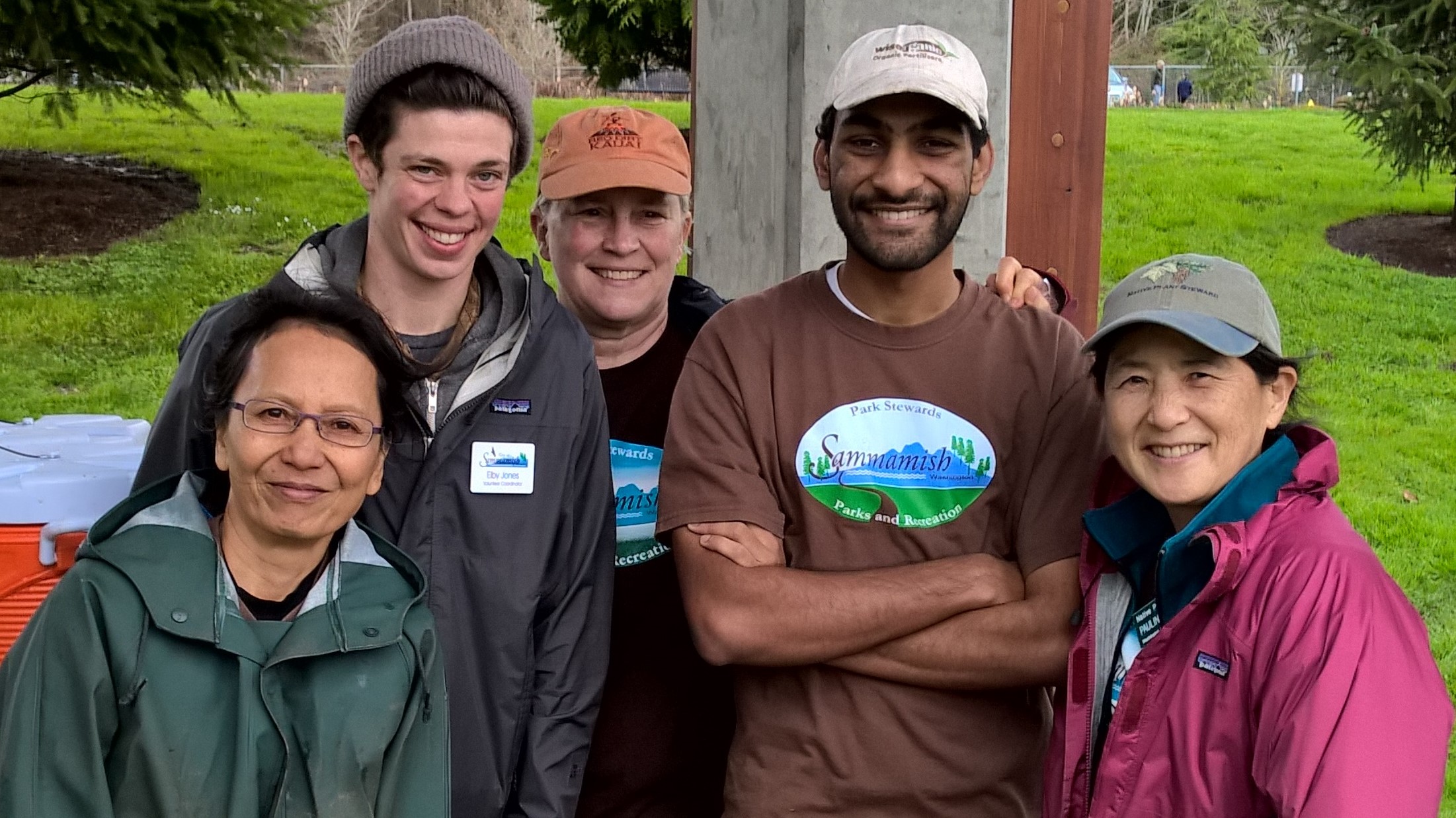 Five people pose in a Sammamish Park, some wearing T-shirts that say Park Stewards - Sammamish Parks and Recreation