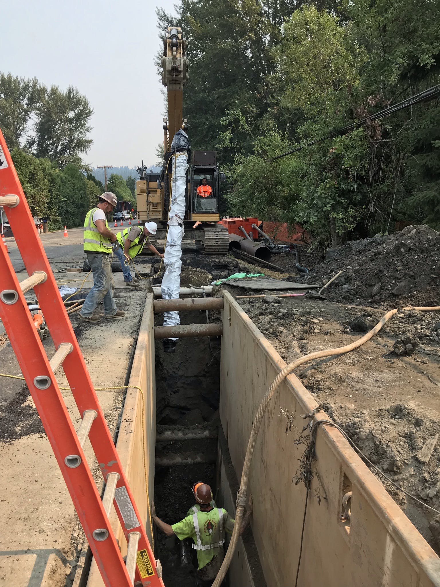 Three crew members work together to install a new water pipe as part of the Ebright Creek Fish Passage project.