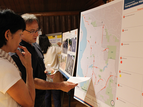 Two people stand at an informational poster board at a Transportation Master Plan public workshop at Beaver Lake Lodge.