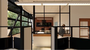 Office interior showing front desk and bulletin board in the background and two workstations, each with dual computer monitors in the foreground.