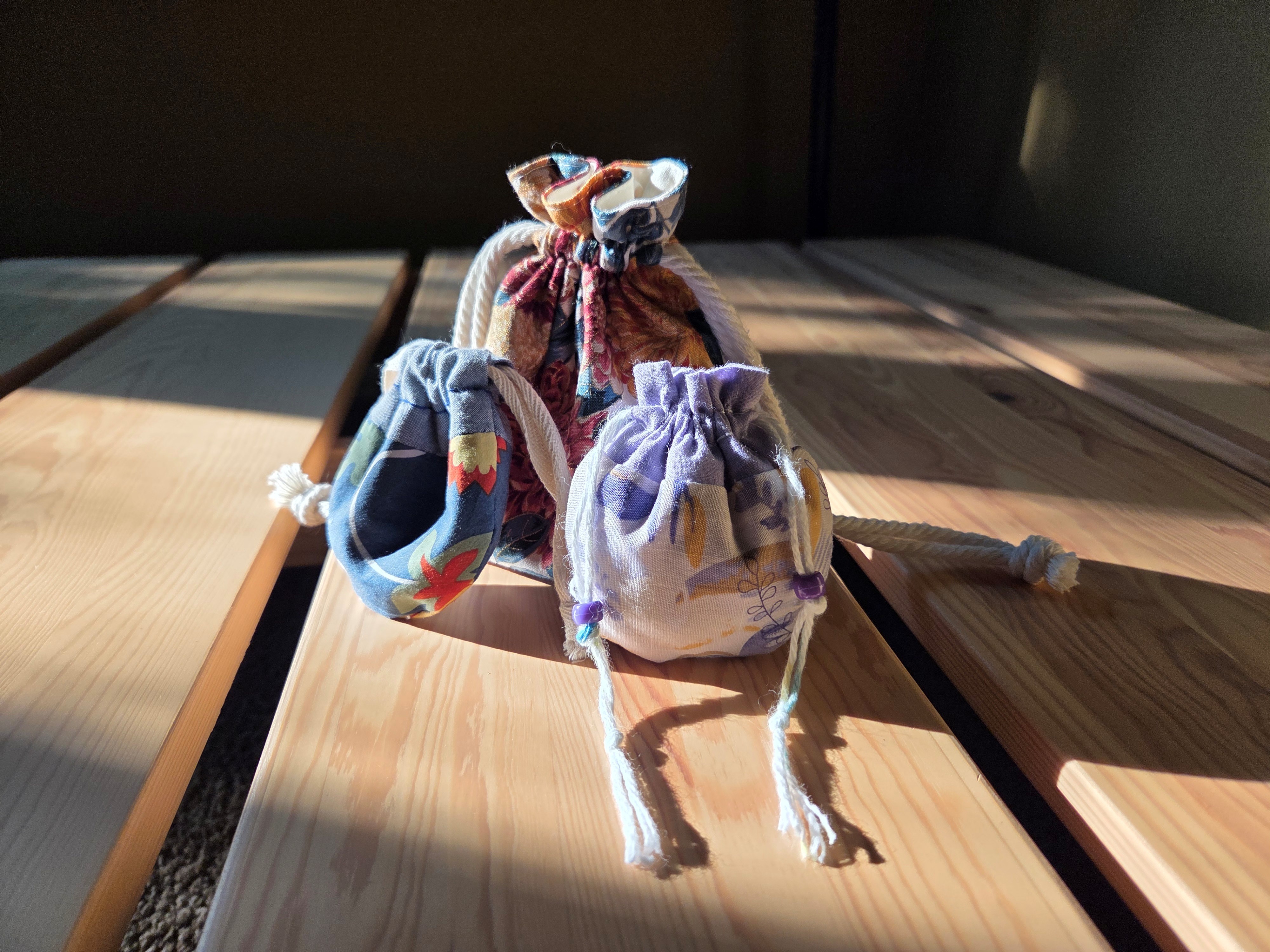 Three Hebao pouches, made of colorful, patterned fabric with yarn drawstrings.