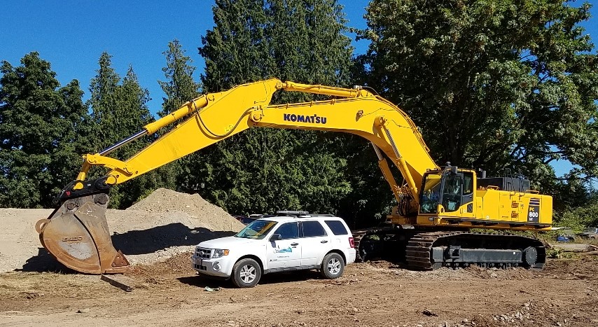 large excavator with arm arching over the top of a City of Sammamish SUV