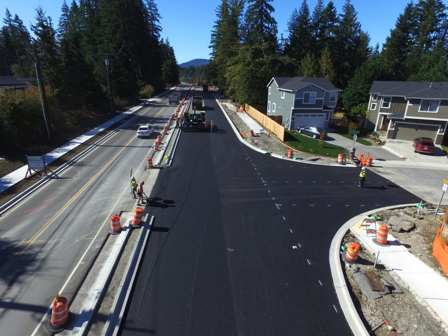 black fresh road surface on two lanes of Issaquah Fall City Road beside the entrance to a housing development