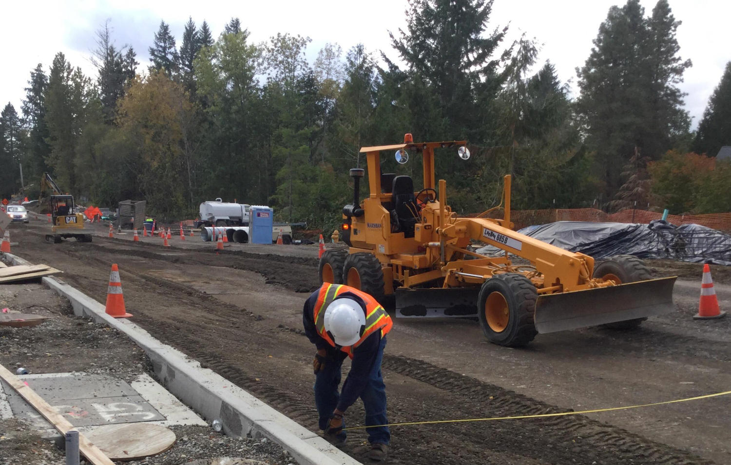 construction worker measuring road width during the road grading process