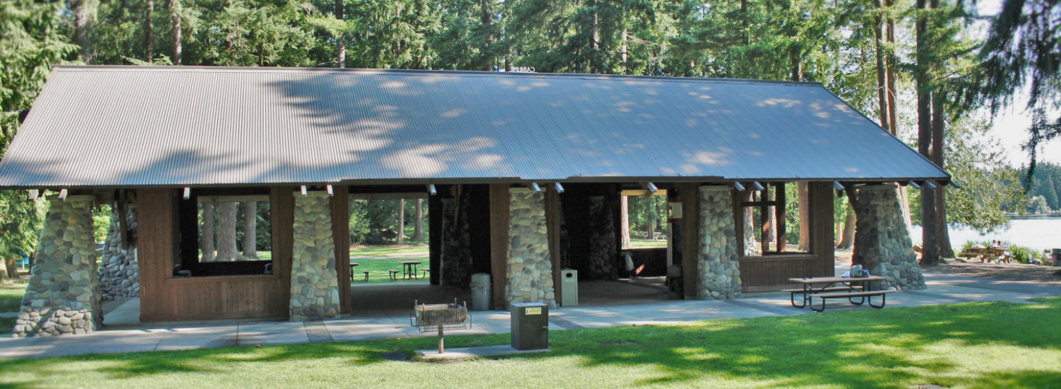 Beaver Lake Pavilion - large open-air wood-frame structure with metal roof and unique triangular-shaped stone support pillars.