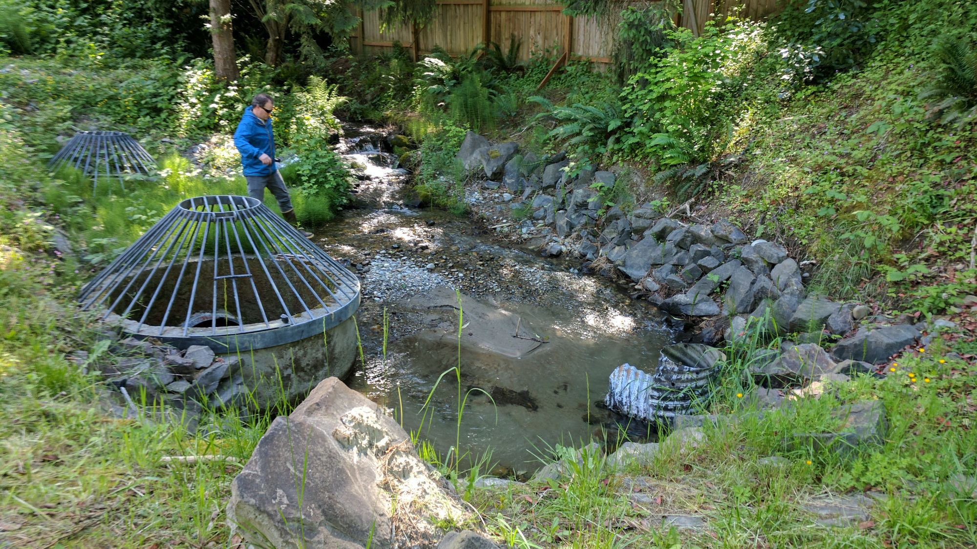 photo of person in rubber boots stepping into sandy sediment pool edged by rock wall