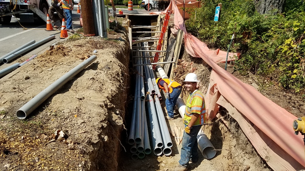 construction workers in trench with pipes ready to be laid